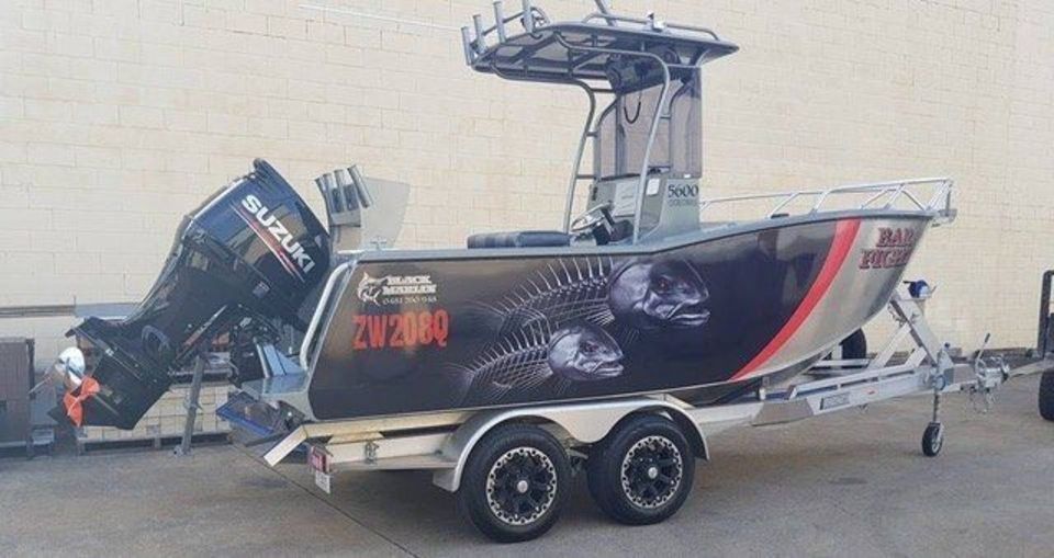A boat with a suzuki outboard motor is parked on a trailer.