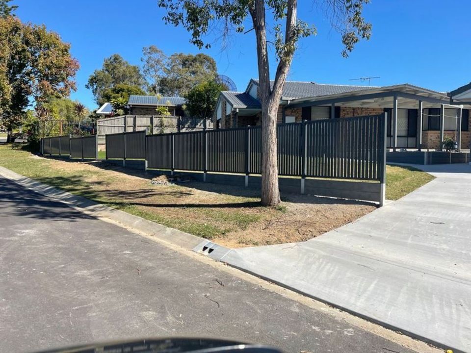 A house with a fence around it and a tree in front of it.