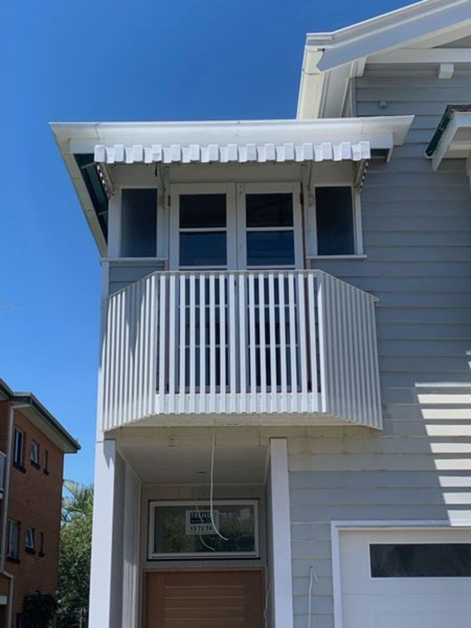 A house with a balcony and a blue sky in the background