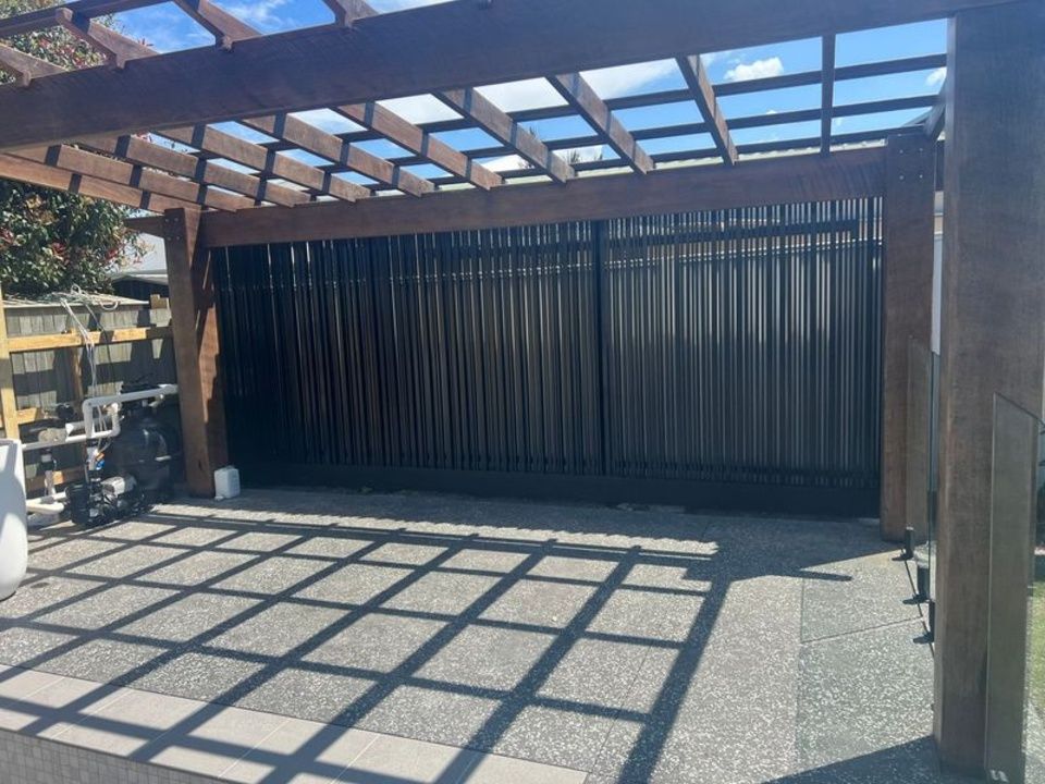 A driveway with a pergola and a sliding gate.