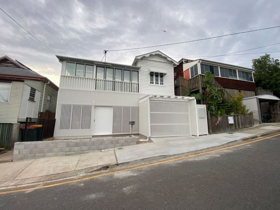 A large white house is sitting on top of a hill next to a street.