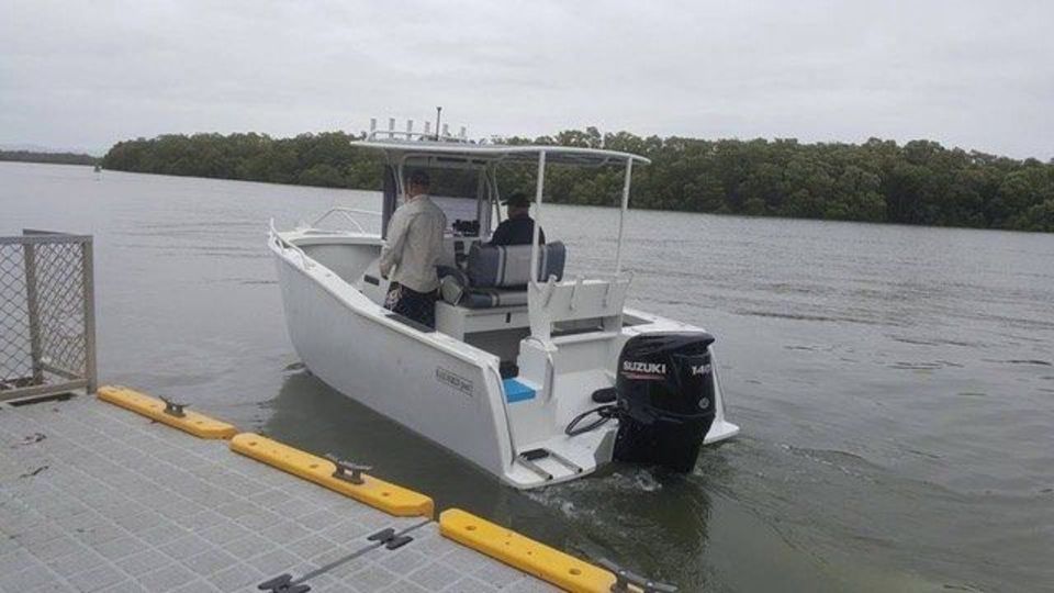 A white boat is docked at a dock in the water.