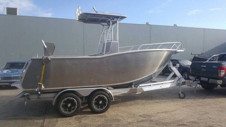 A boat is on a trailer attached to a truck.