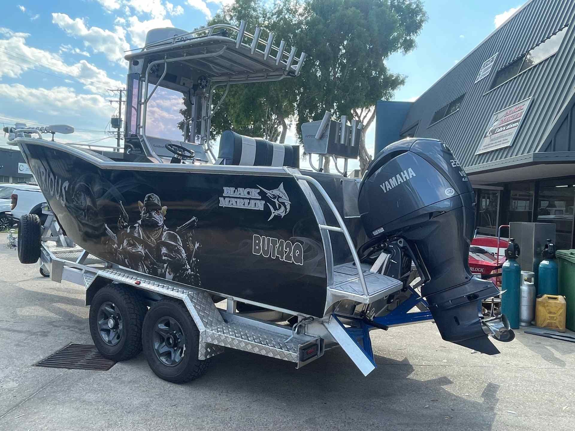 A boat is sitting on a blue tarp in a parking lot