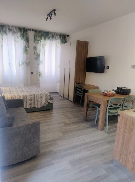 Una mano che mescola un cappuccino schiumoso in una tazza nera Mado, un croissant e dei bicchieri d'acqua su un tavolo.