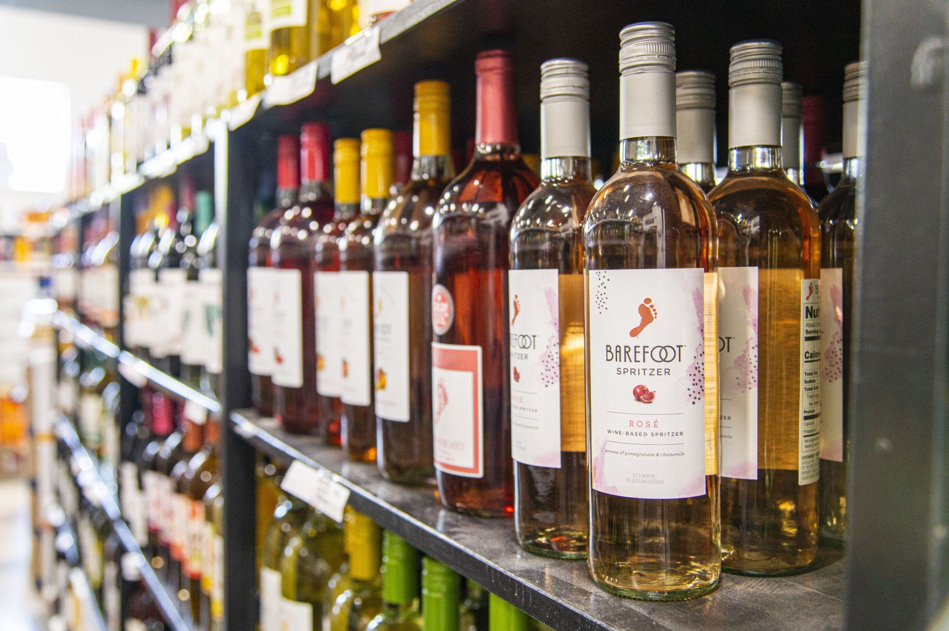 Shelves of wine bottles at a store, featuring rosé and other colors.