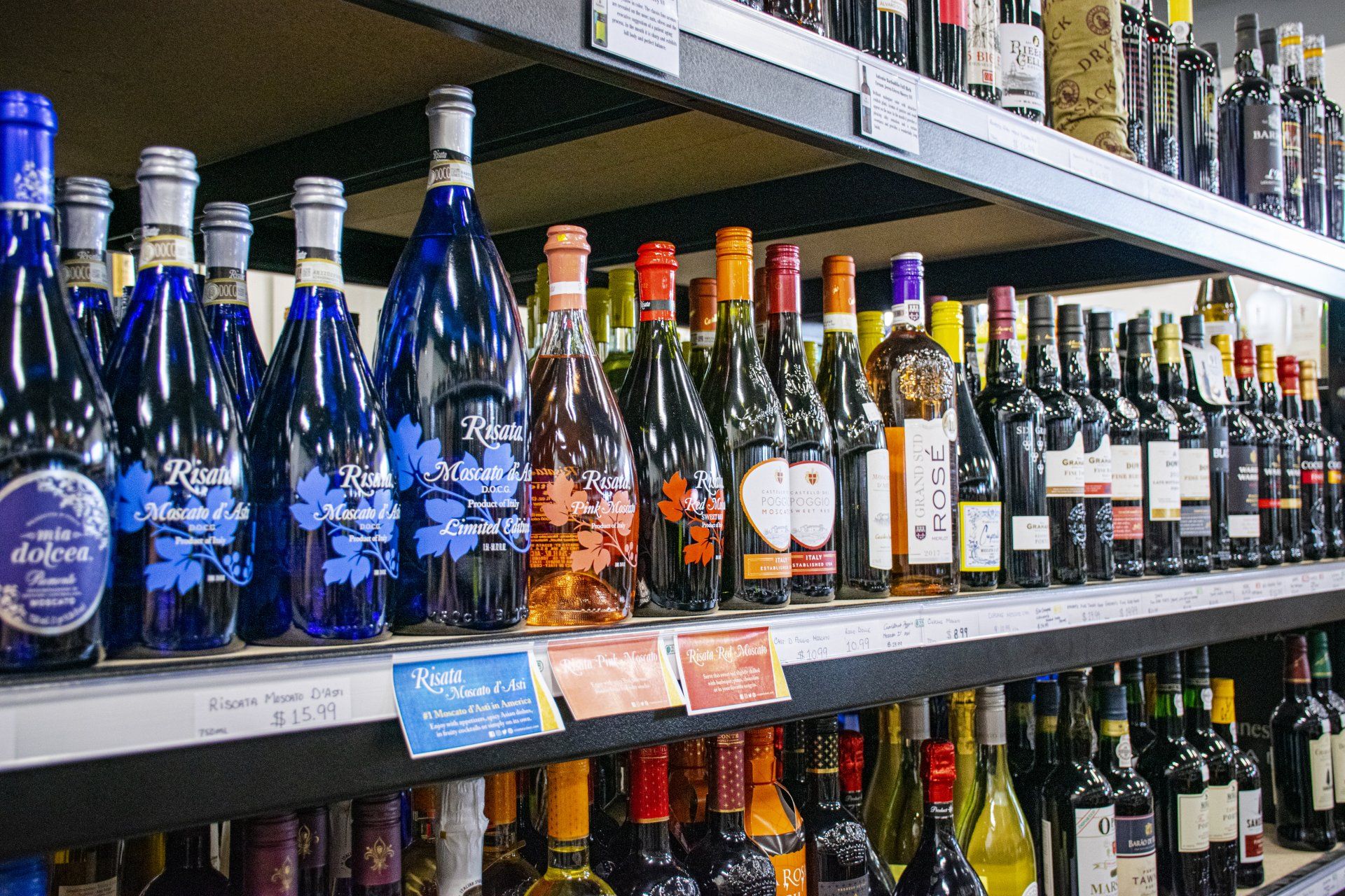 Bottles of wine on shelves at a liquor store, variety of colors, well organized.