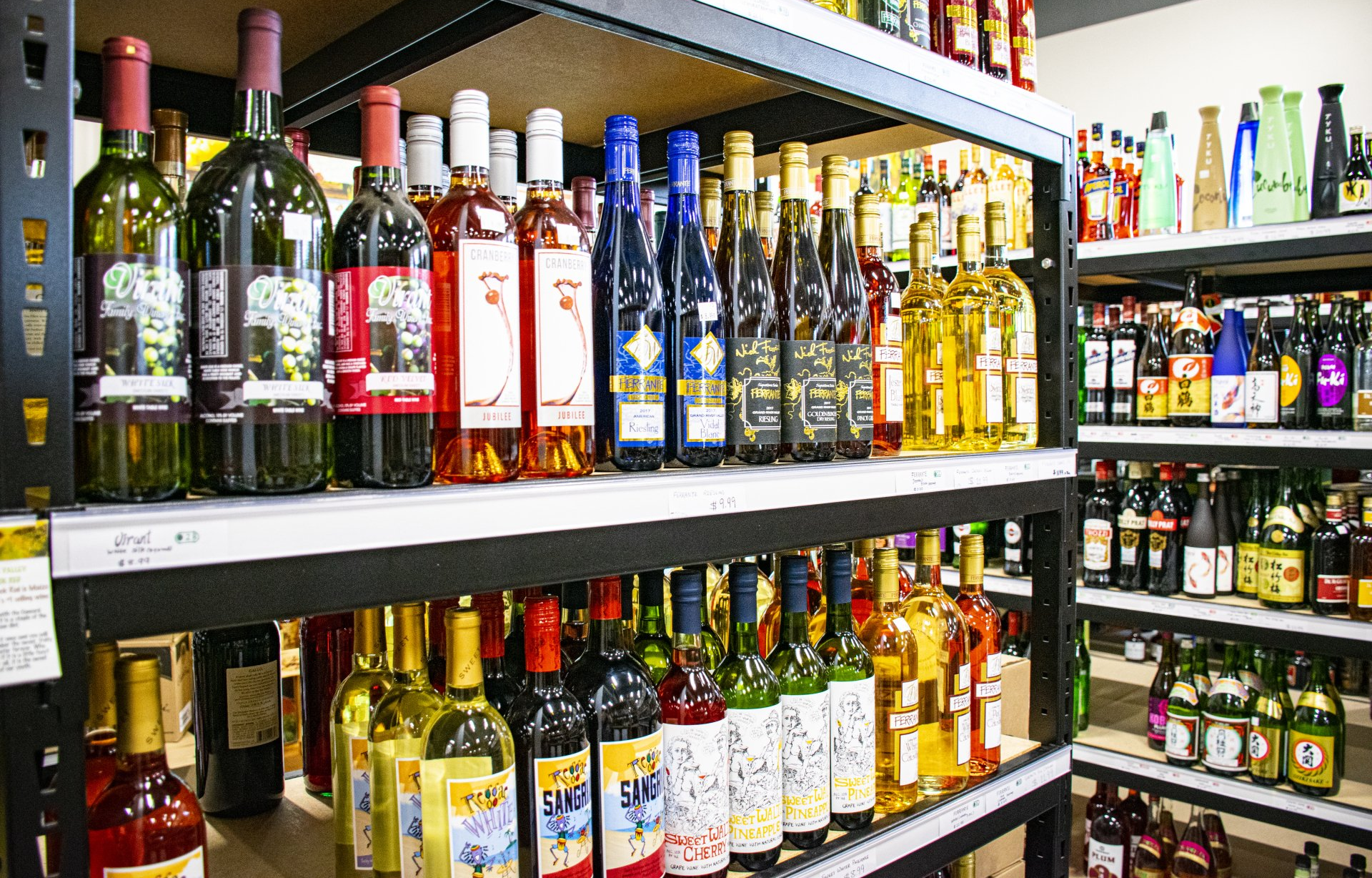Shelves of wine bottles in a store, various colors and shapes.