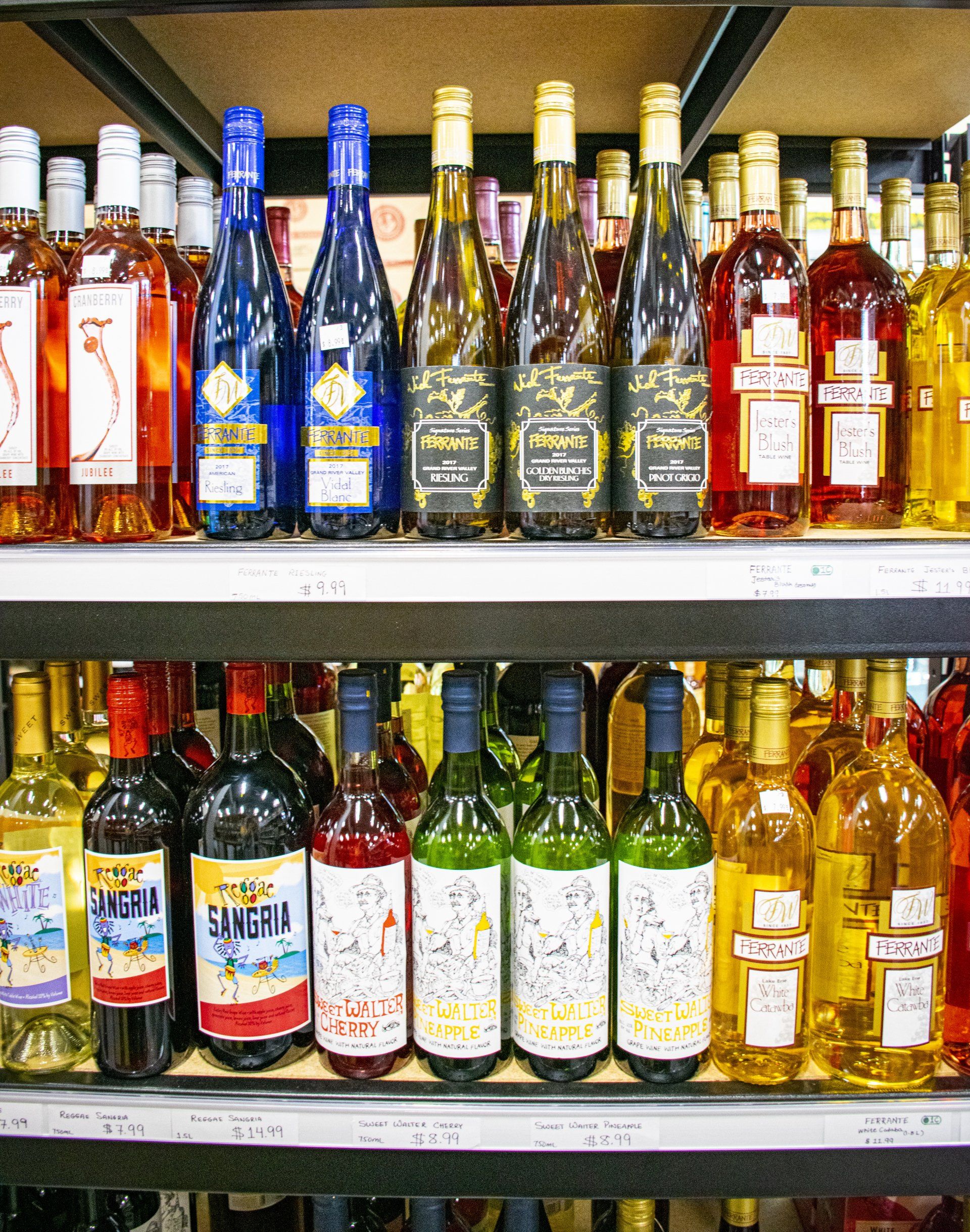 Bottles of various colorful alcoholic beverages displayed on shelves in a store.