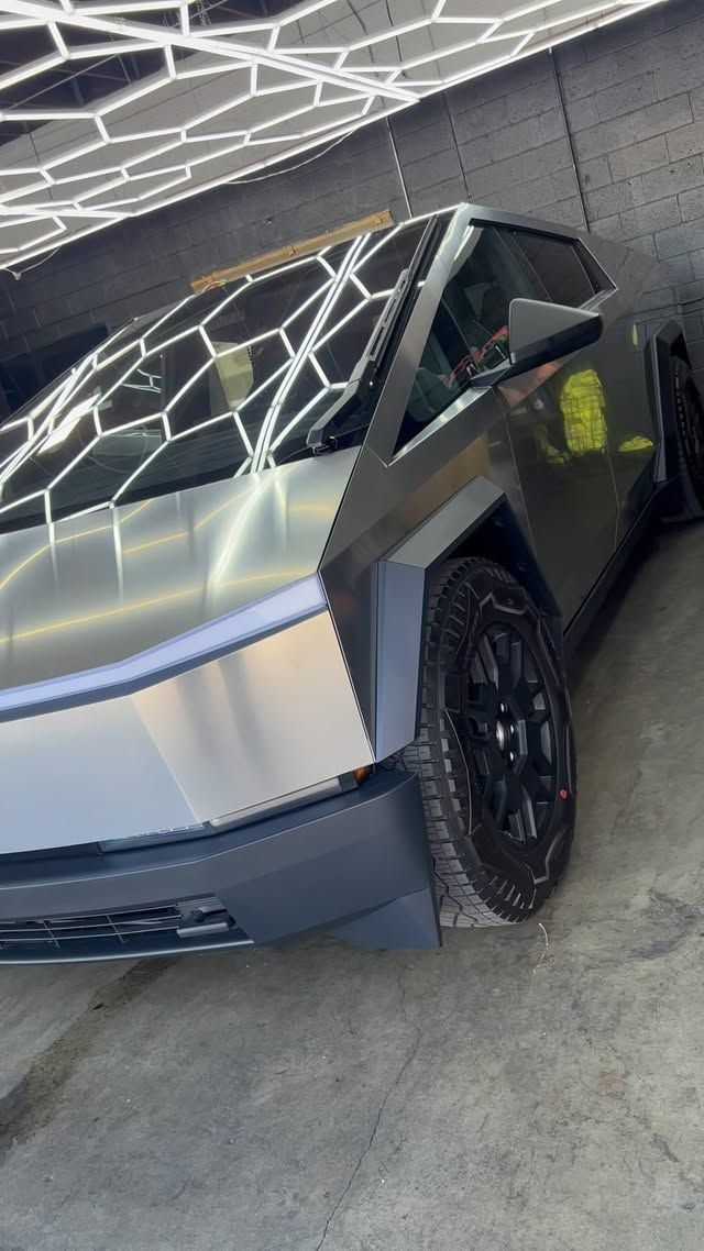 A silver tesla cybertruck is parked in a garage.