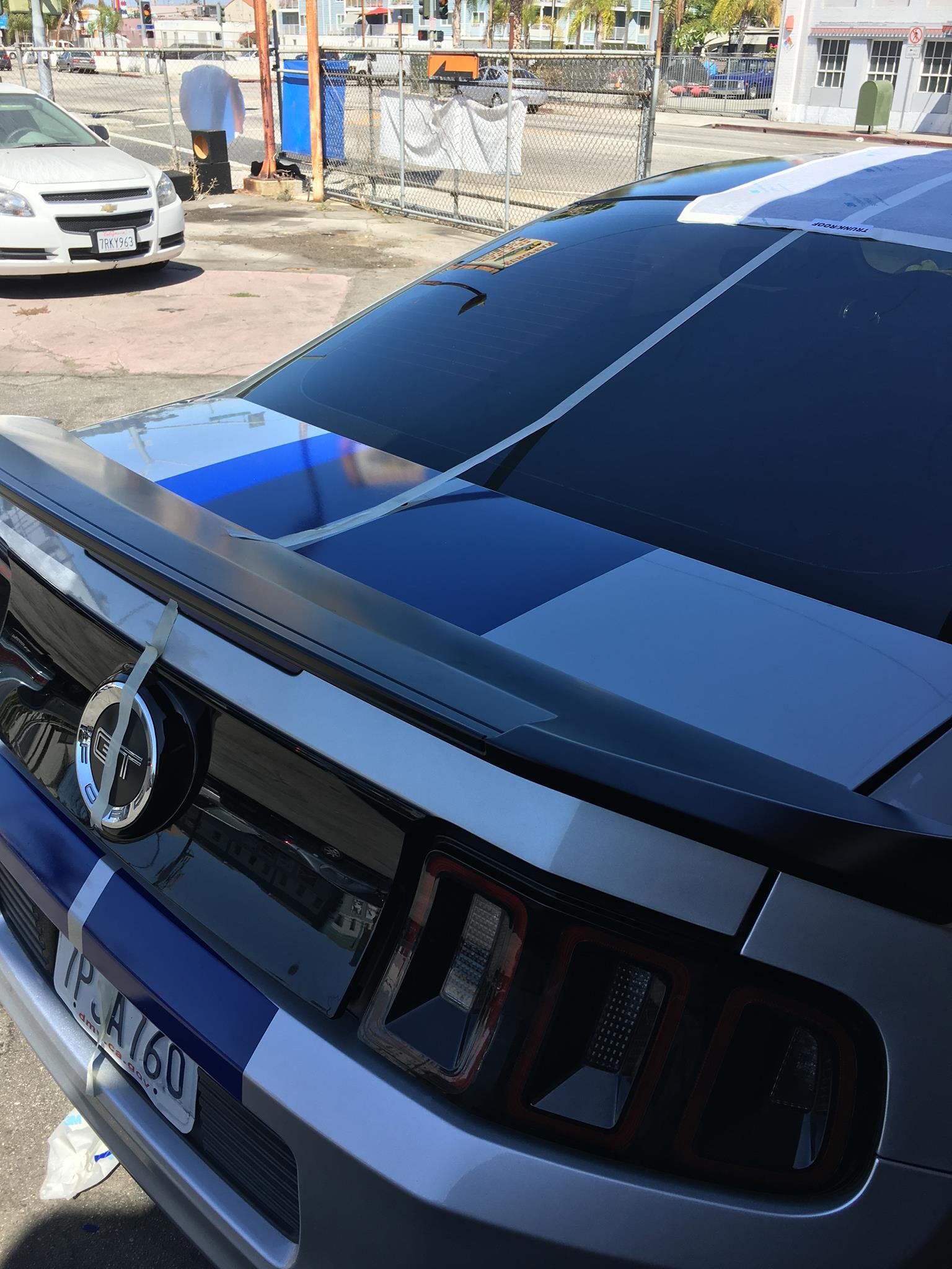 A blue and white mustang is parked in a parking lot.