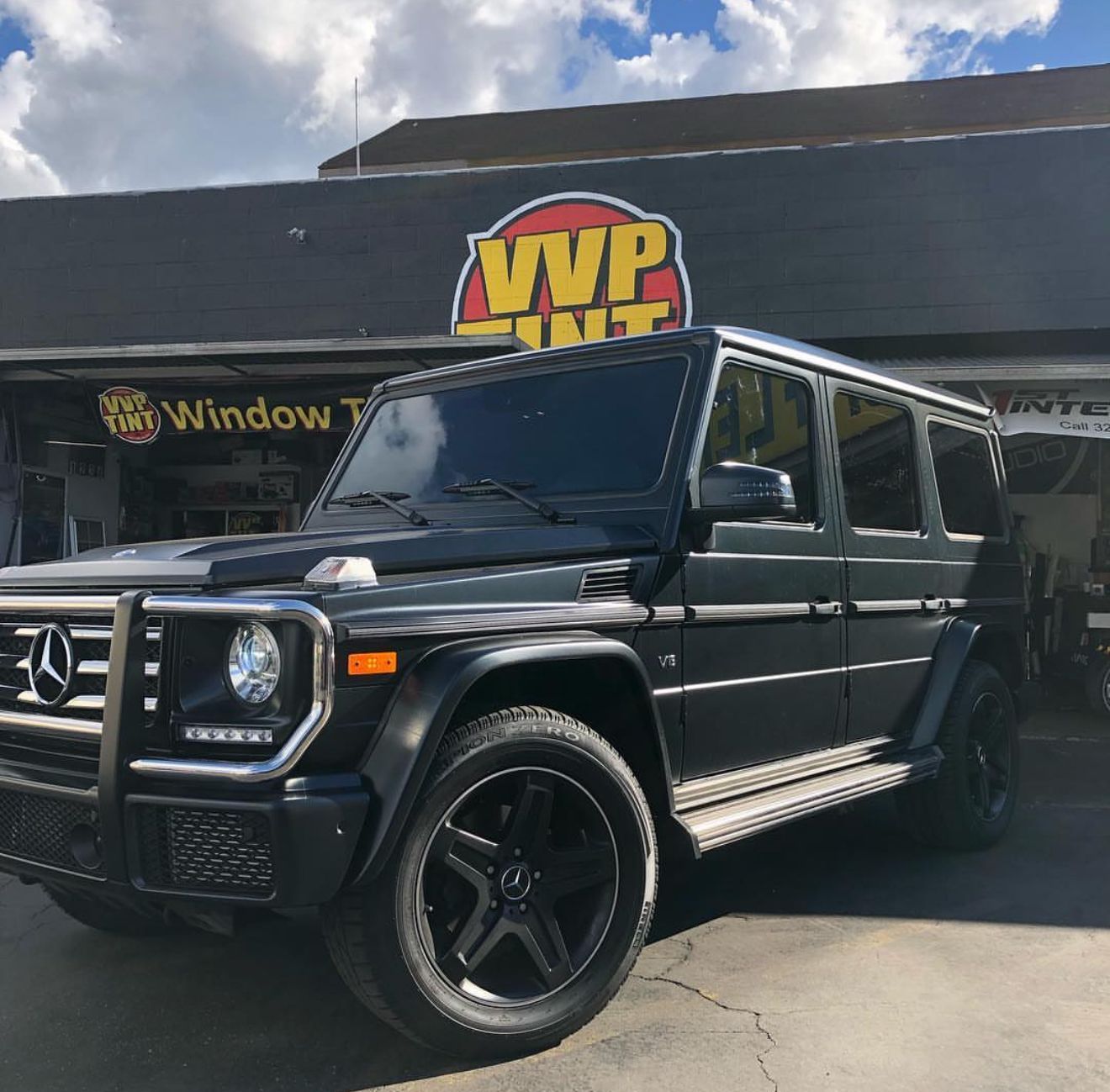 A white car with the hood up is sitting in a garage.