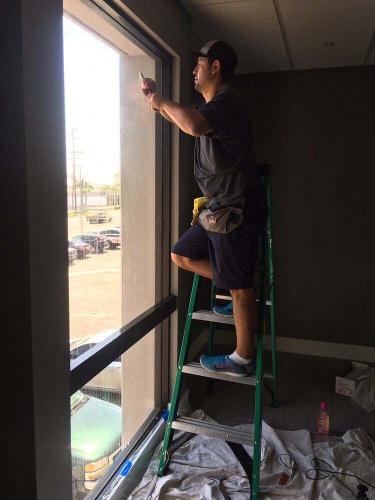 A man is standing on a ladder cleaning a window.