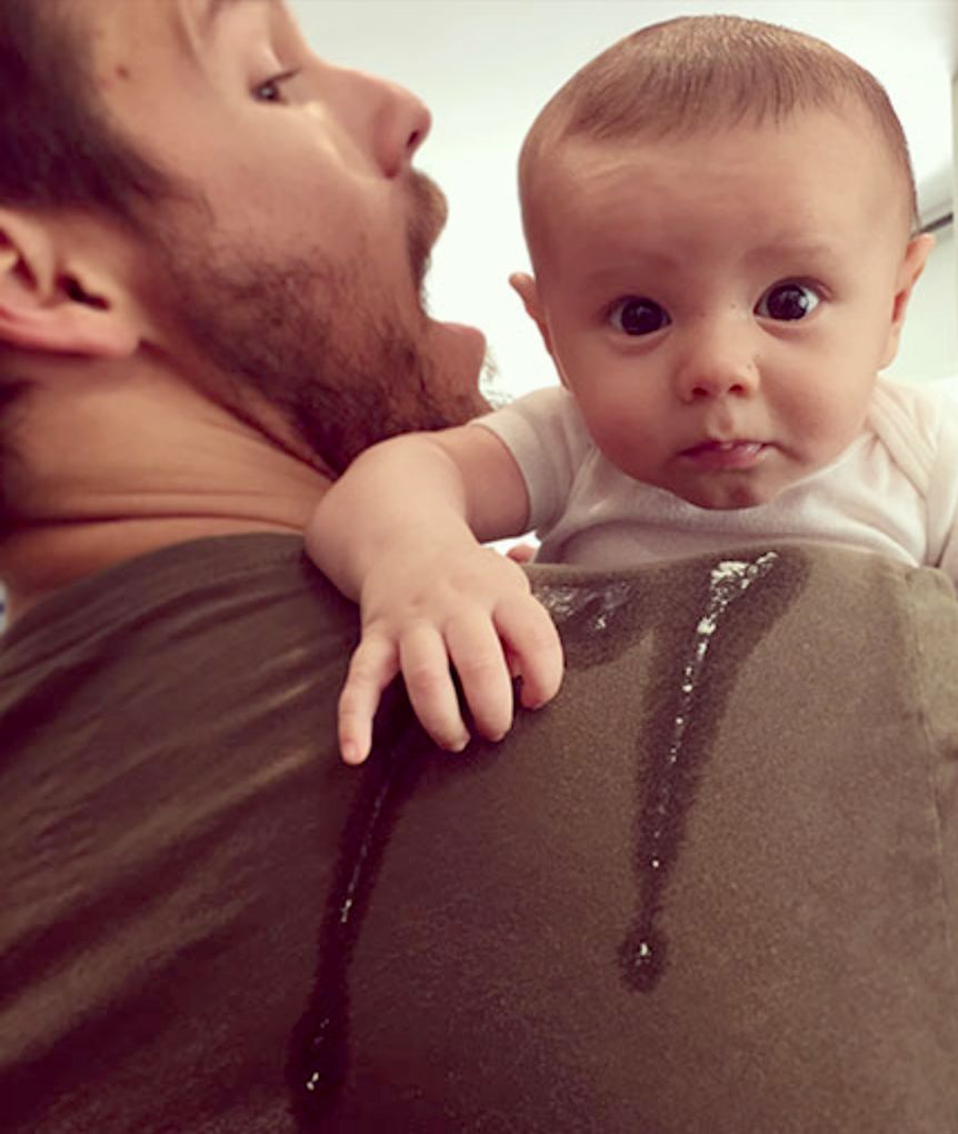 A man is holding a baby over his shoulder.