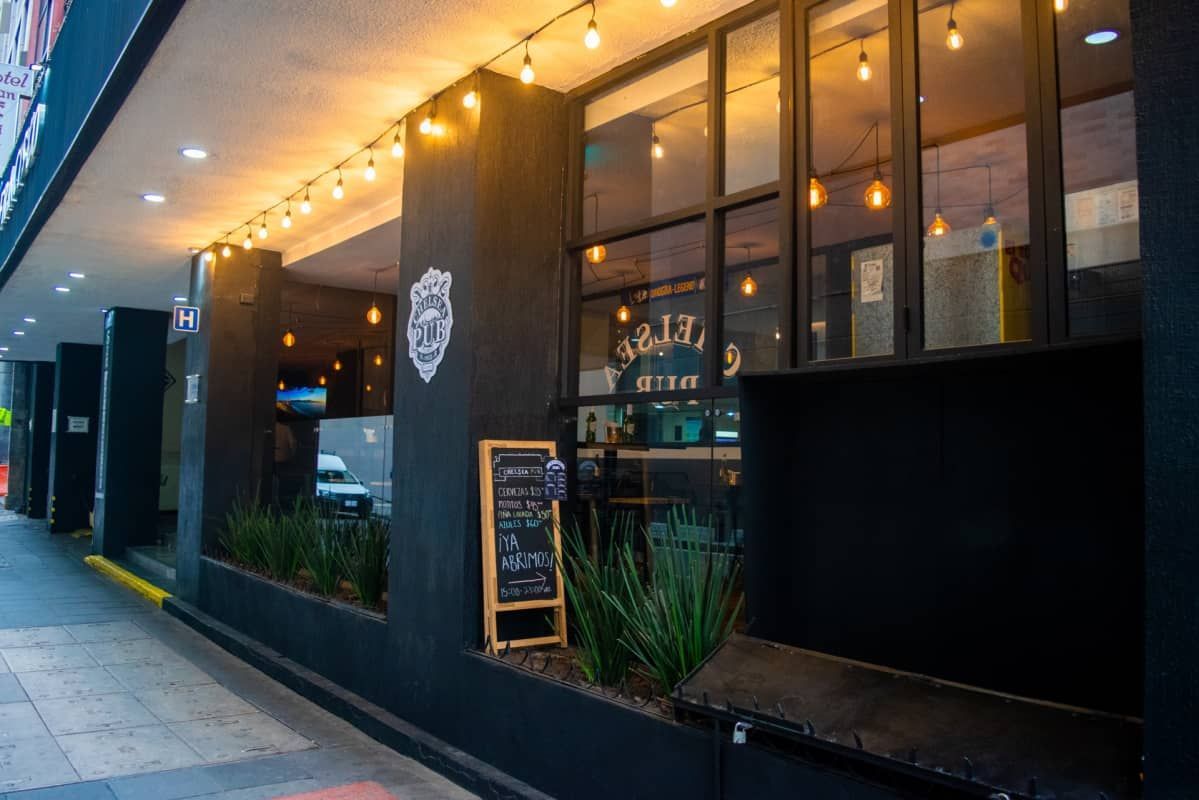 Un restaurante con muchas ventanas y una pizarra delante.