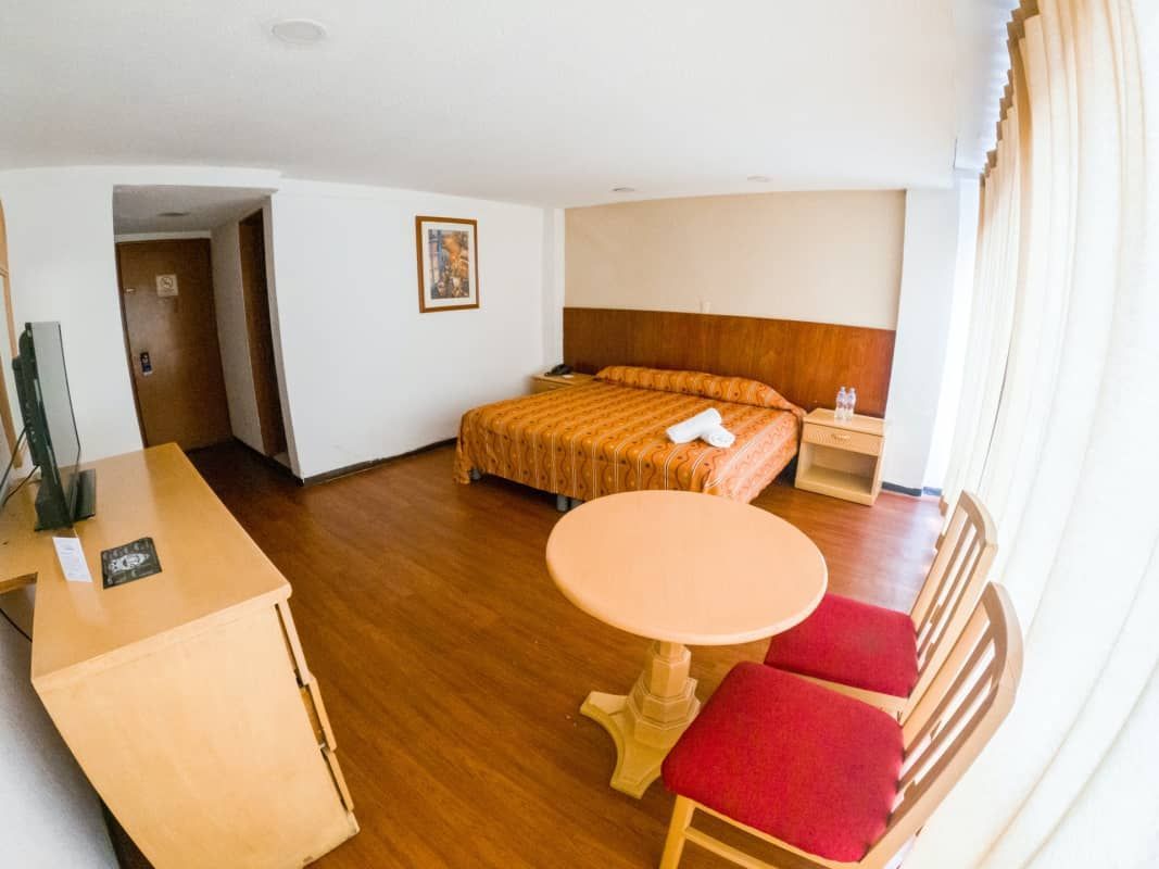 Una habitación de hotel con una cama, mesa y sillas.