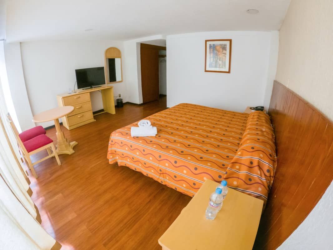 Una habitación de hotel con una cama tamaño king y un televisor.