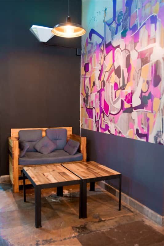 Una habitación con un sofá y dos mesas y un mural en la pared.