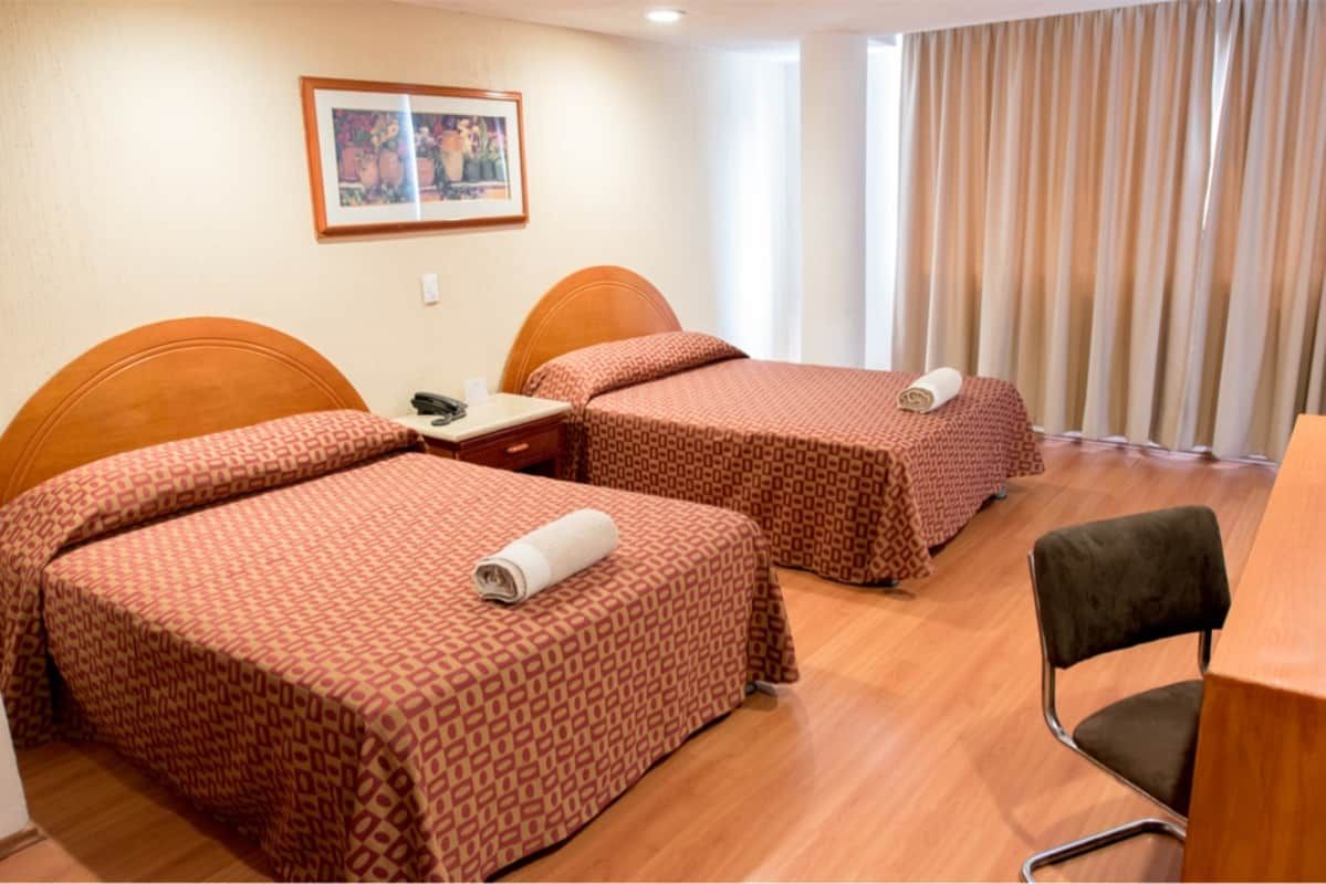 Una habitación de hotel con dos camas y una silla.