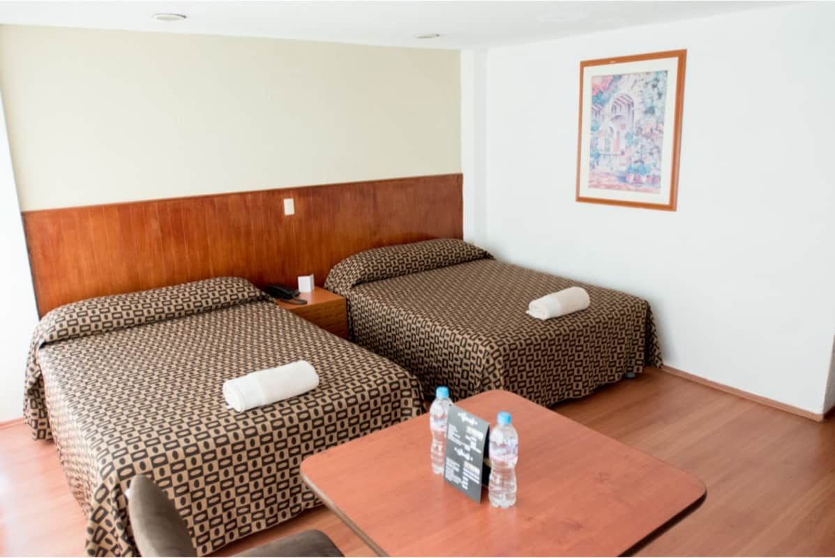 Una habitación de hotel con dos camas y una mesa.