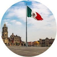 Una bandera mexicana ondea en el viento frente a una ciudad.