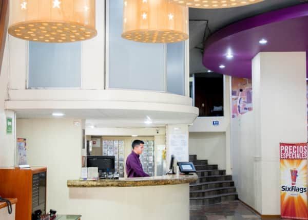 Un hombre se encuentra detrás de un mostrador en una habitación con un cartel que dice 