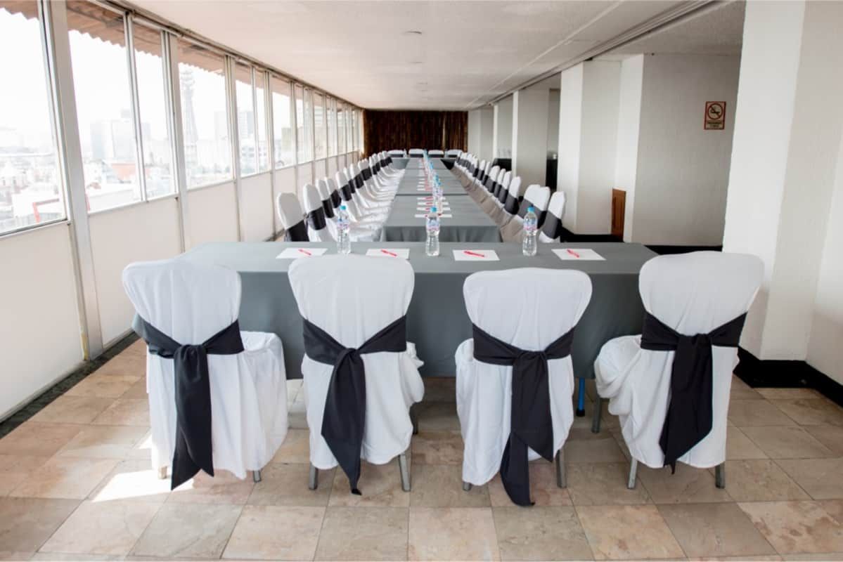 Una mesa larga y sillas en una habitación con muchas ventanas.