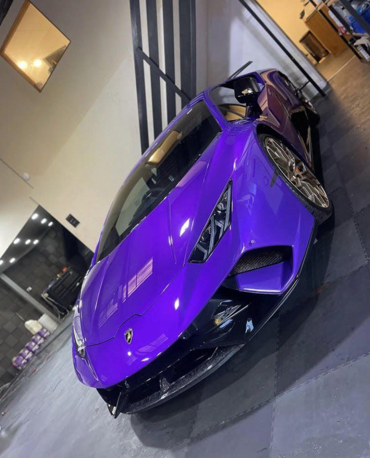 A purple lamborghini is parked in a garage gleaming