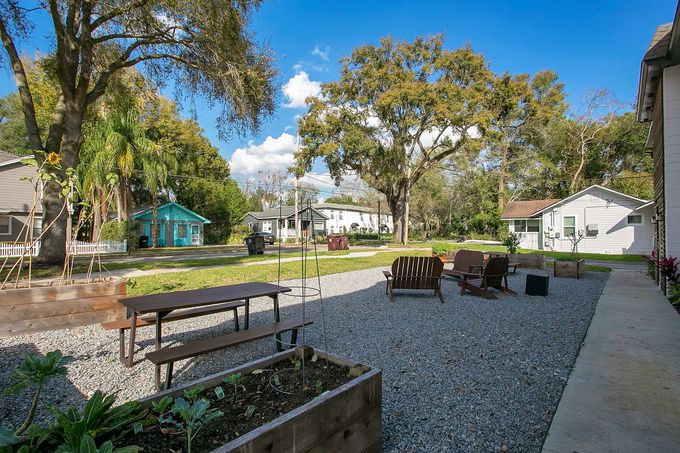 A patio with a picnic table , chairs and a planter.