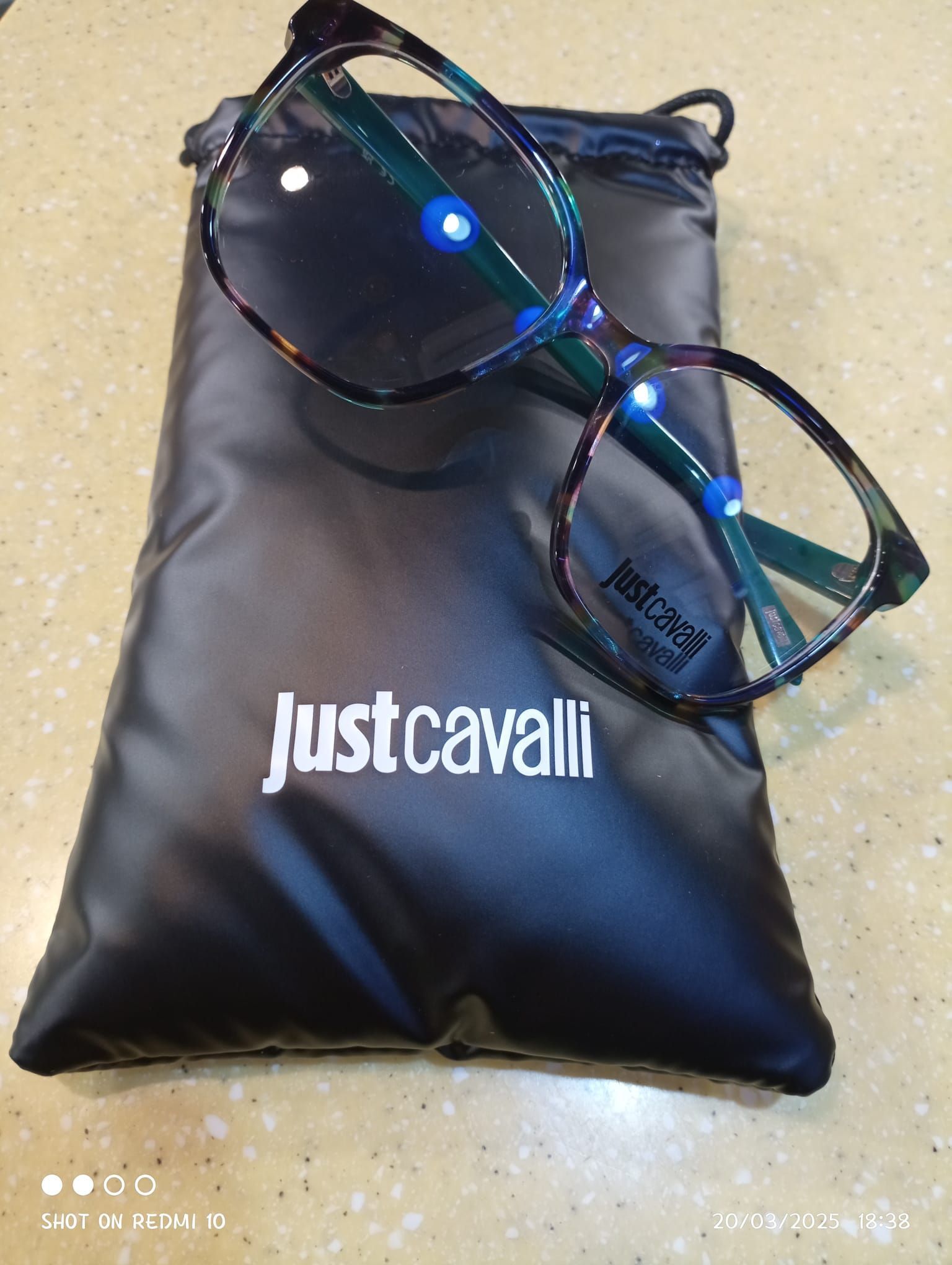 Un paio di occhiali appoggiati sopra una borsa Just Cavalli.
