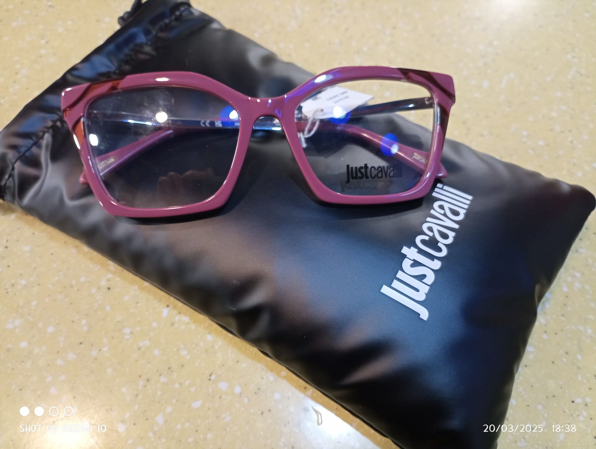 Un paio di occhiali è appoggiato sopra una borsa justcavalli.