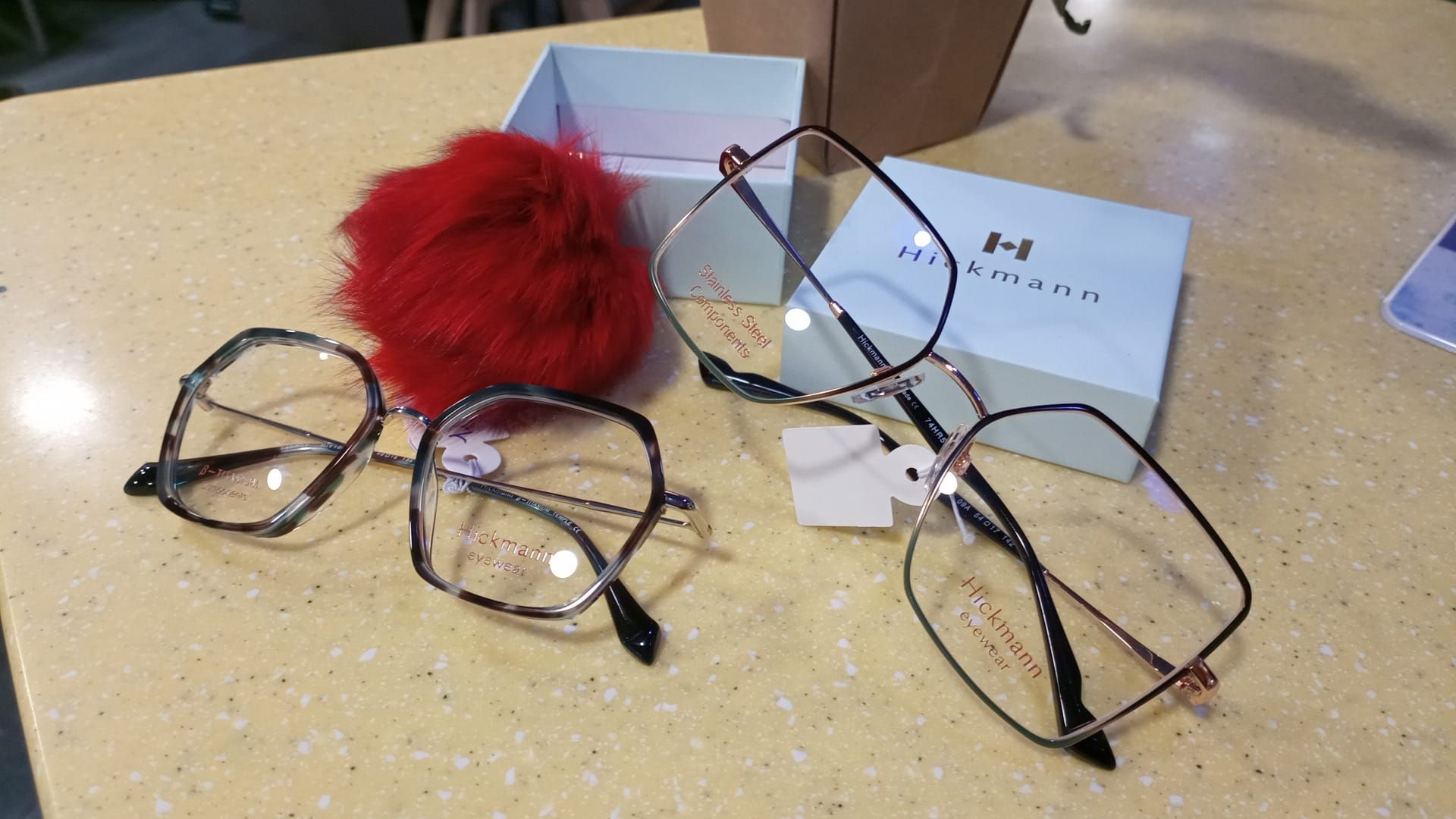 Un paio di occhiali appoggiati su un tavolo accanto a una scatola con la lettera h sopra