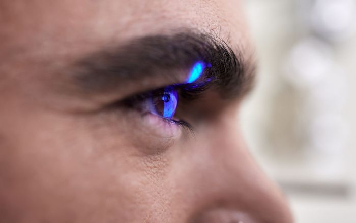 Un primo piano dell'occhio di un uomo illuminato da una luce blu.