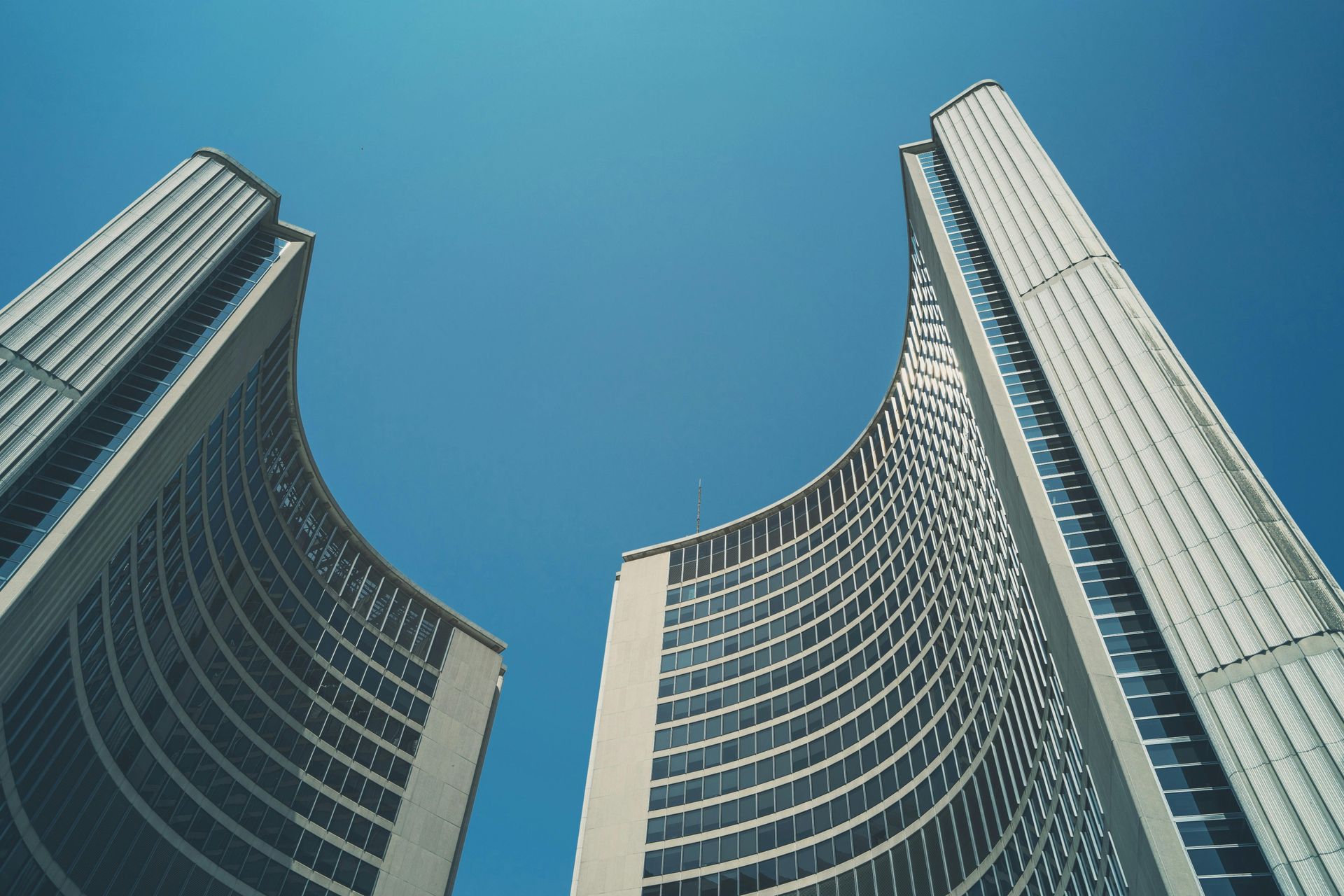 Looking up at two tall buildings against a blue sky.