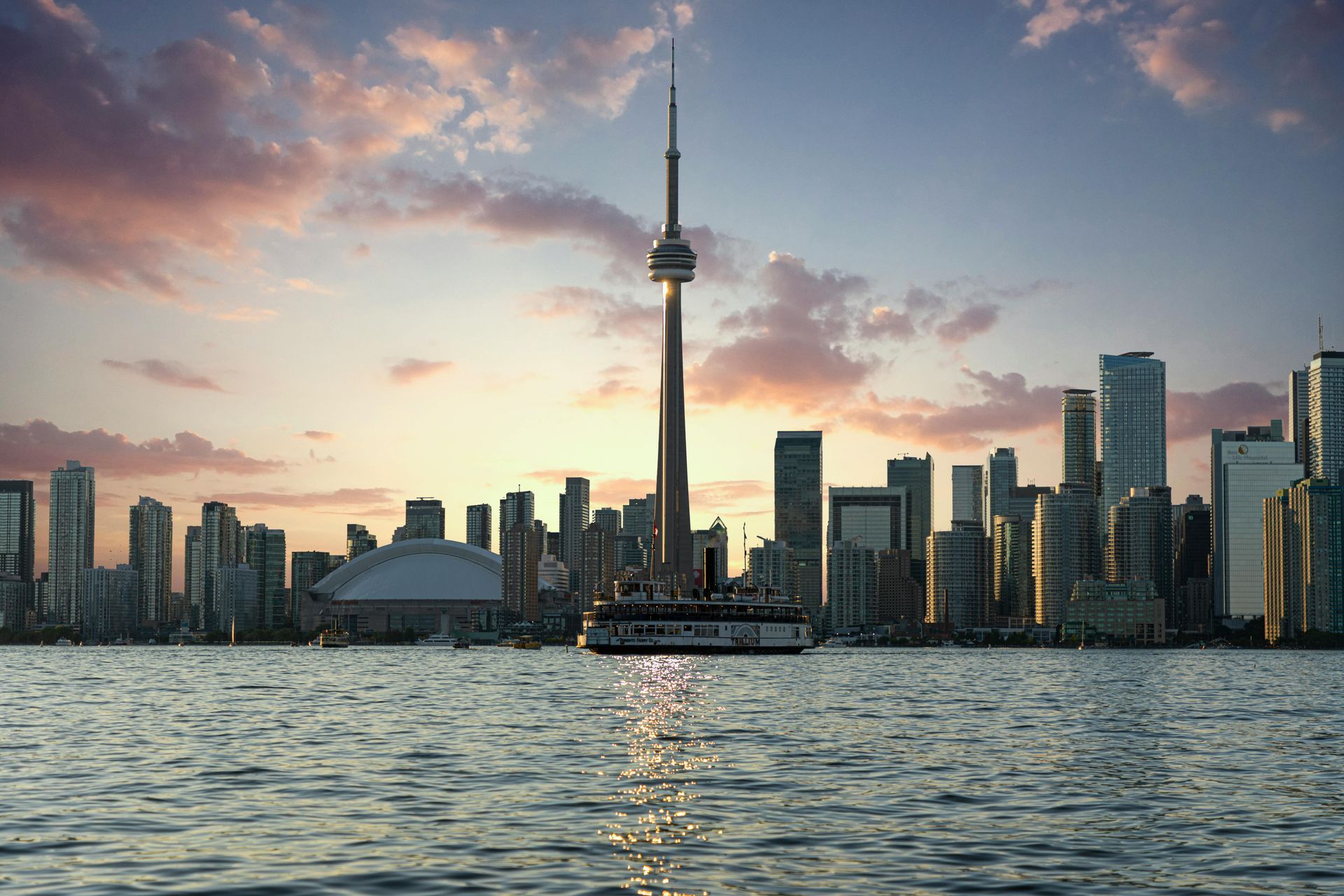 The toronto skyline is visible from the water at sunset.