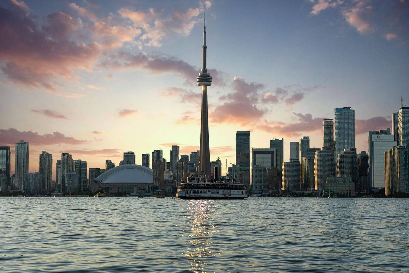 The toronto skyline is visible from the water at sunset.