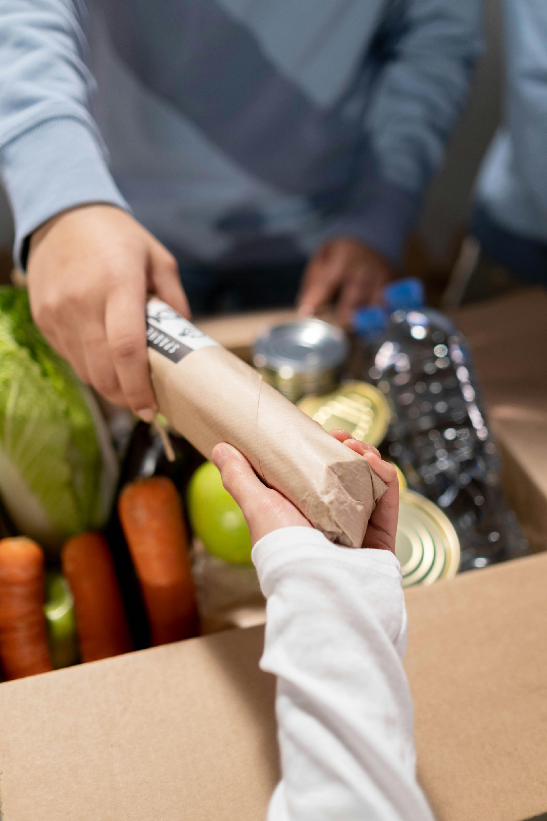 A person is giving a box of food to another person.