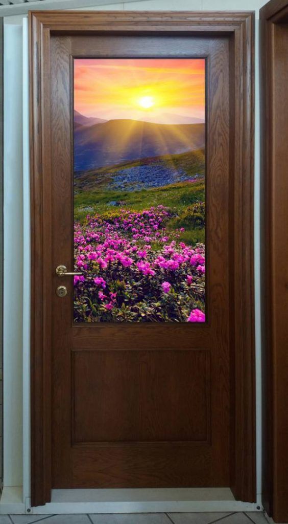 Una porta di legno con l'immagine di un tramonto e dei fiori.