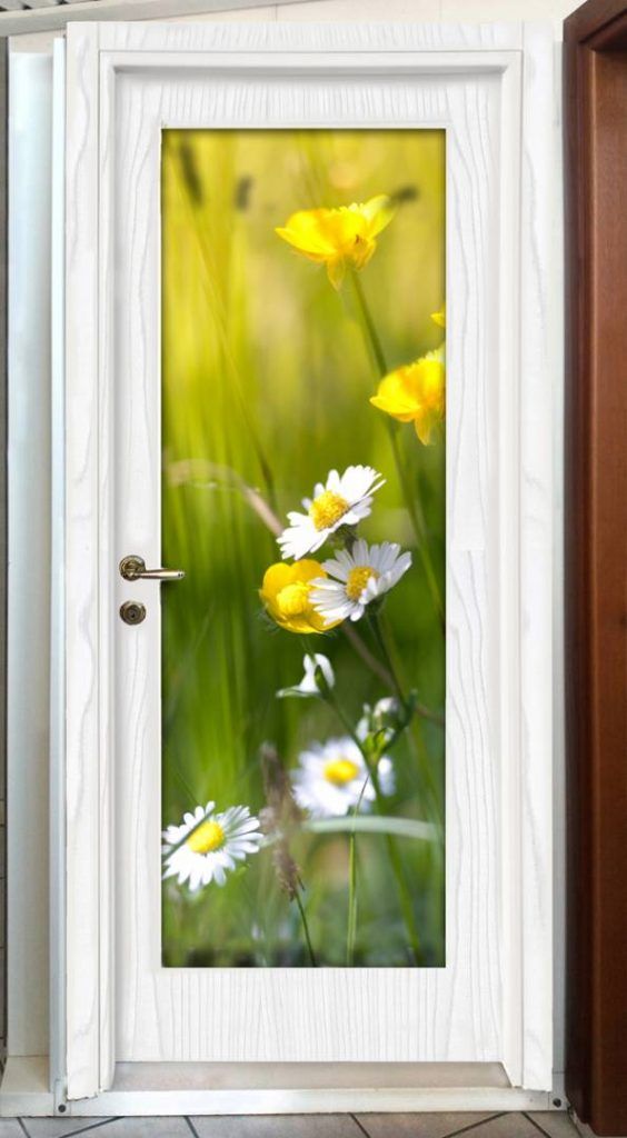 Una porta bianca con sopra raffigurate margherite e fiori gialli.