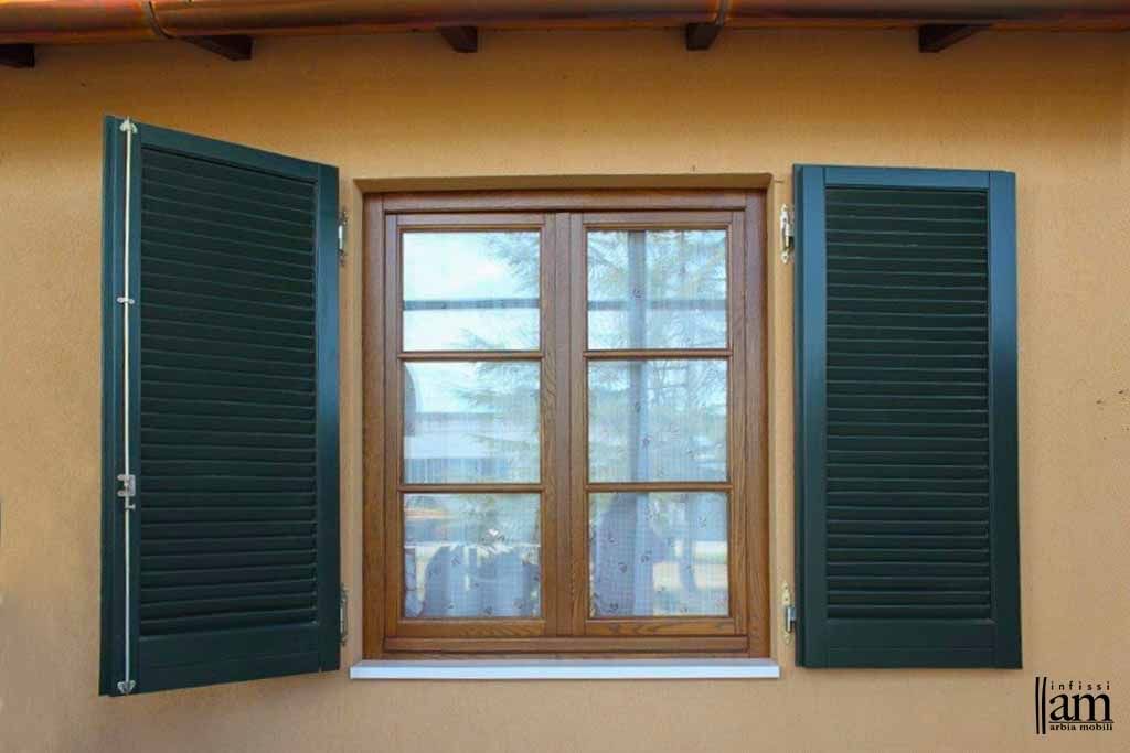 Una finestra con persiane verdi su un muro giallo