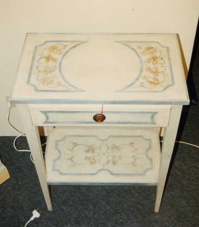 Un tavolino bianco con un cassetto e uno scaffale