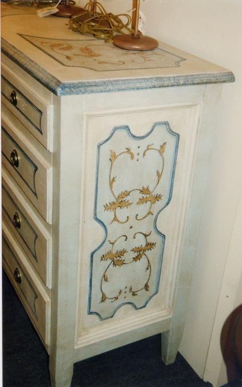 Una cassettiera bianca con un disegno blu e oro sul lato