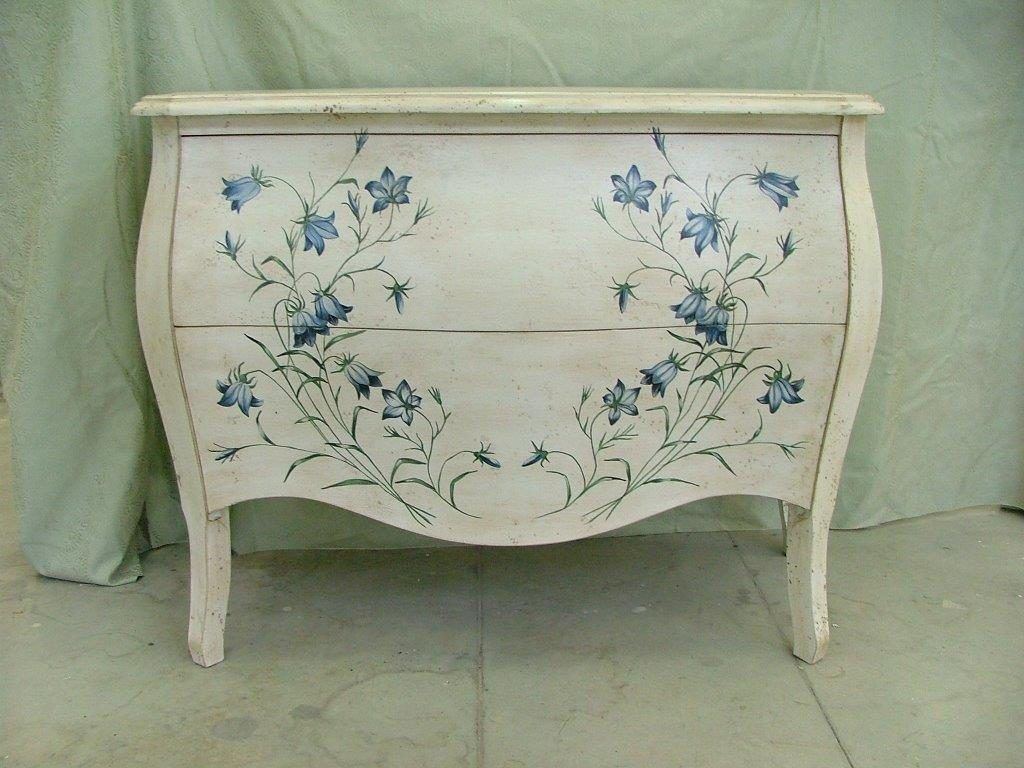 Una cassettiera bianca con fiori blu dipinti sopra