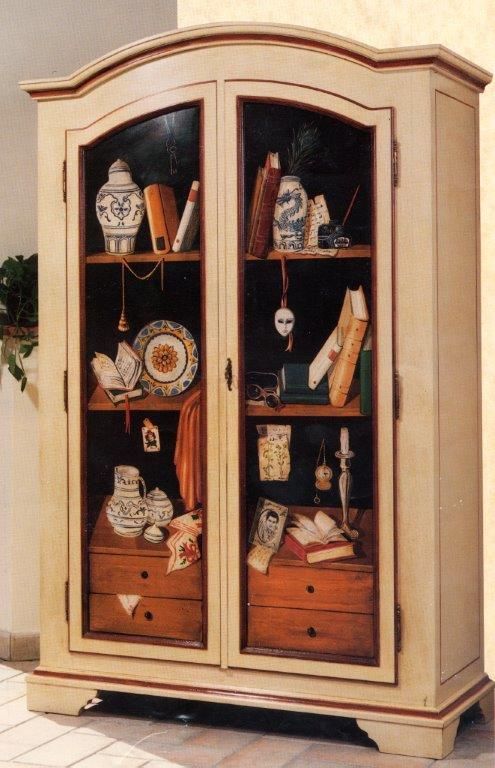 Un mobile bianco con ante in vetro pieno di vari oggetti