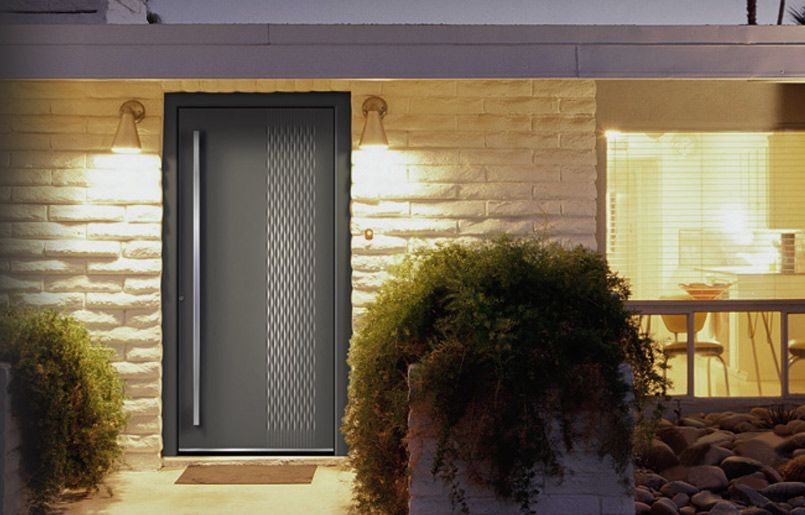 Una casa di mattoni con una porta grigia e una finestra di notte.