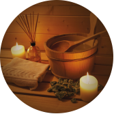 Un seau en bois avec une cuillère dedans est posé sur une table en bois à côté de bougies et d'une serviette.