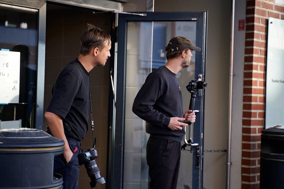 To produktfotografer som står med hvert sitt kamera