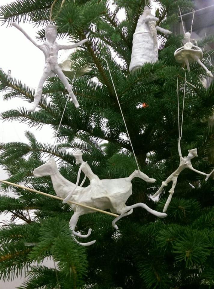 Christmas tree decorated with paper mache figures of people and a horse.