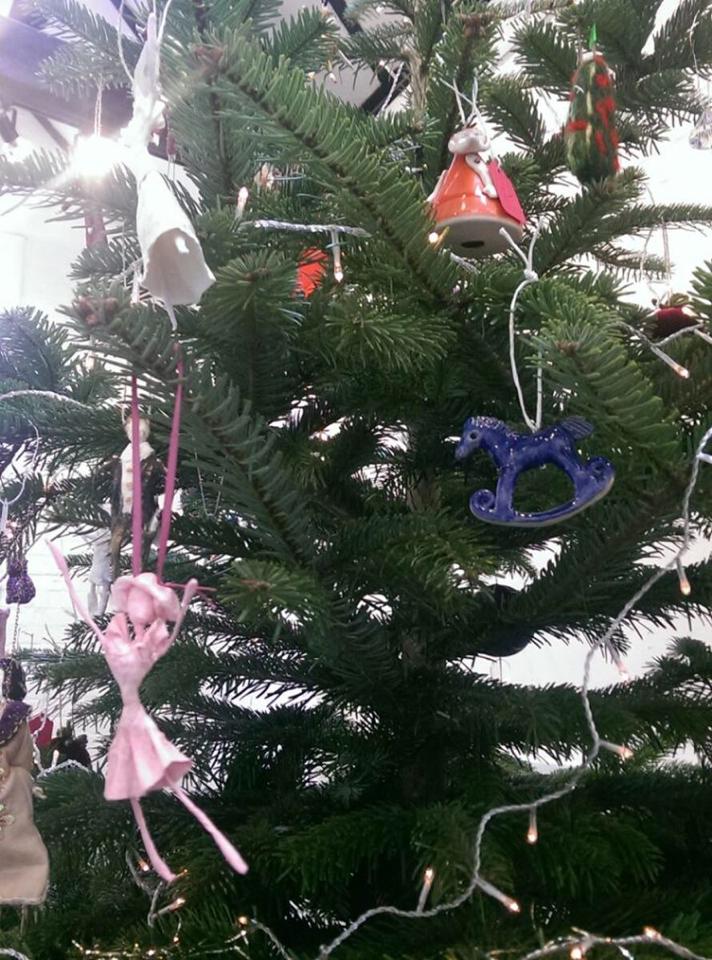 Christmas tree decorated with ornaments, including a pink dancer and a blue rocking horse.