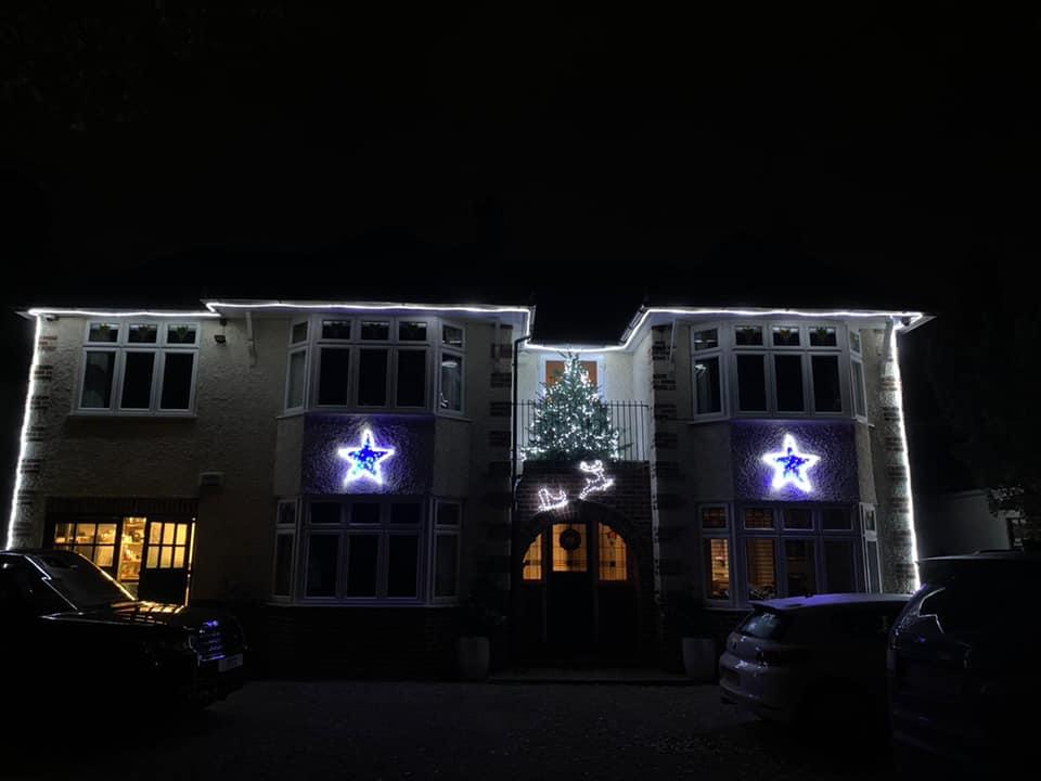 House decorated with white lights and blue star displays for Christmas, at night.